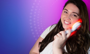 woman using clinical led light therapy on her face and smiling