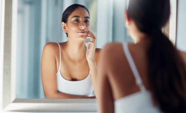 Attractive girl admiring her skin in the bathroom mirror.