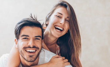 Young couple laughing and smiling with bright teeth.