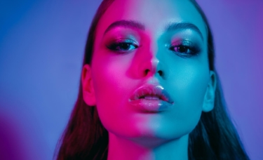 High fashion model with red and blue lights shining on her skin.