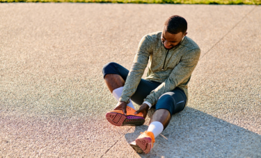 Black male runner with neuropathy holding his hurt foot.