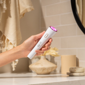 Lux Collection Glo has LED lights on and is in the hands of a woman in front of a bathroom counter