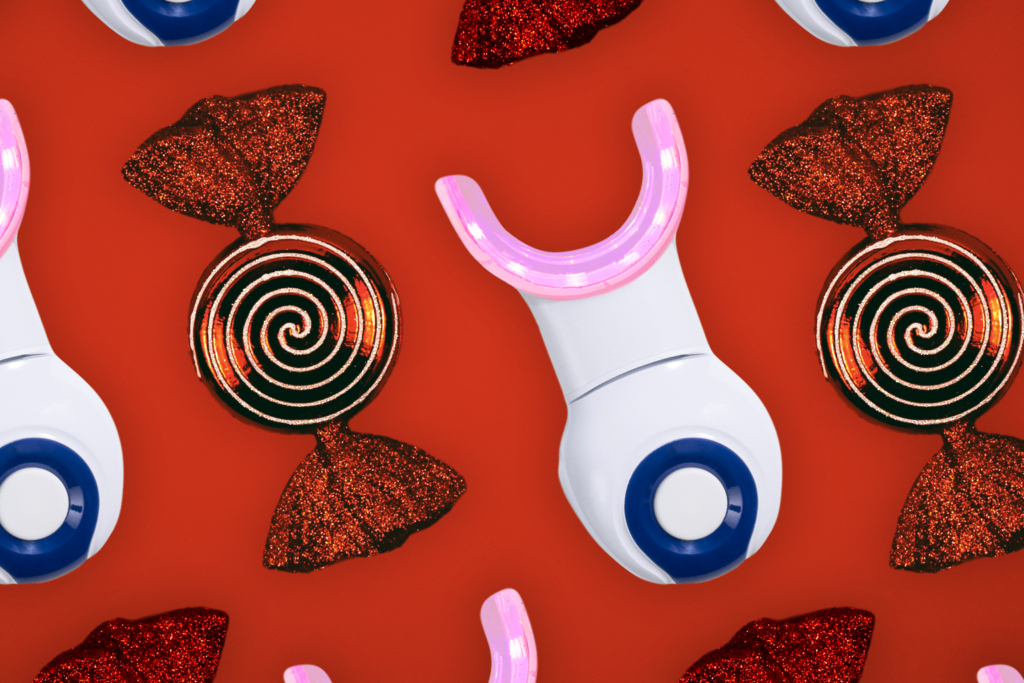 Several dpl Oral Care light therapy devices lie on a red background. The LED lights are on, giving a purple glow. 