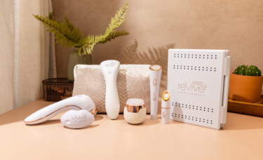 seven Lux Collection devices are arranged on a bathroom counter. The counter looks warm and cozy, with plants and a makeup bag in the background.