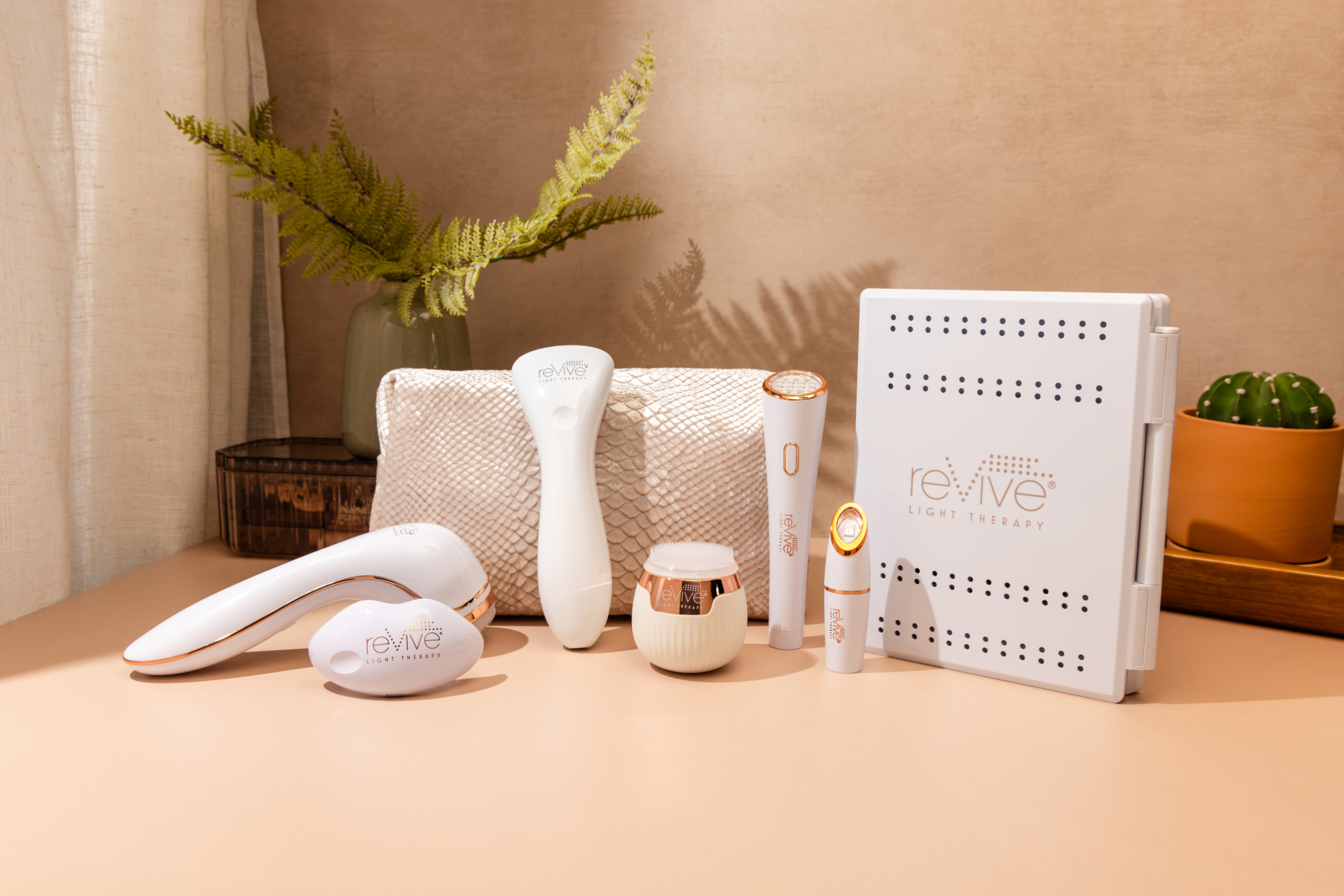 seven Lux Collection devices are arranged on a bathroom counter. The counter looks warm and cozy, with plants and a makeup bag in the background.