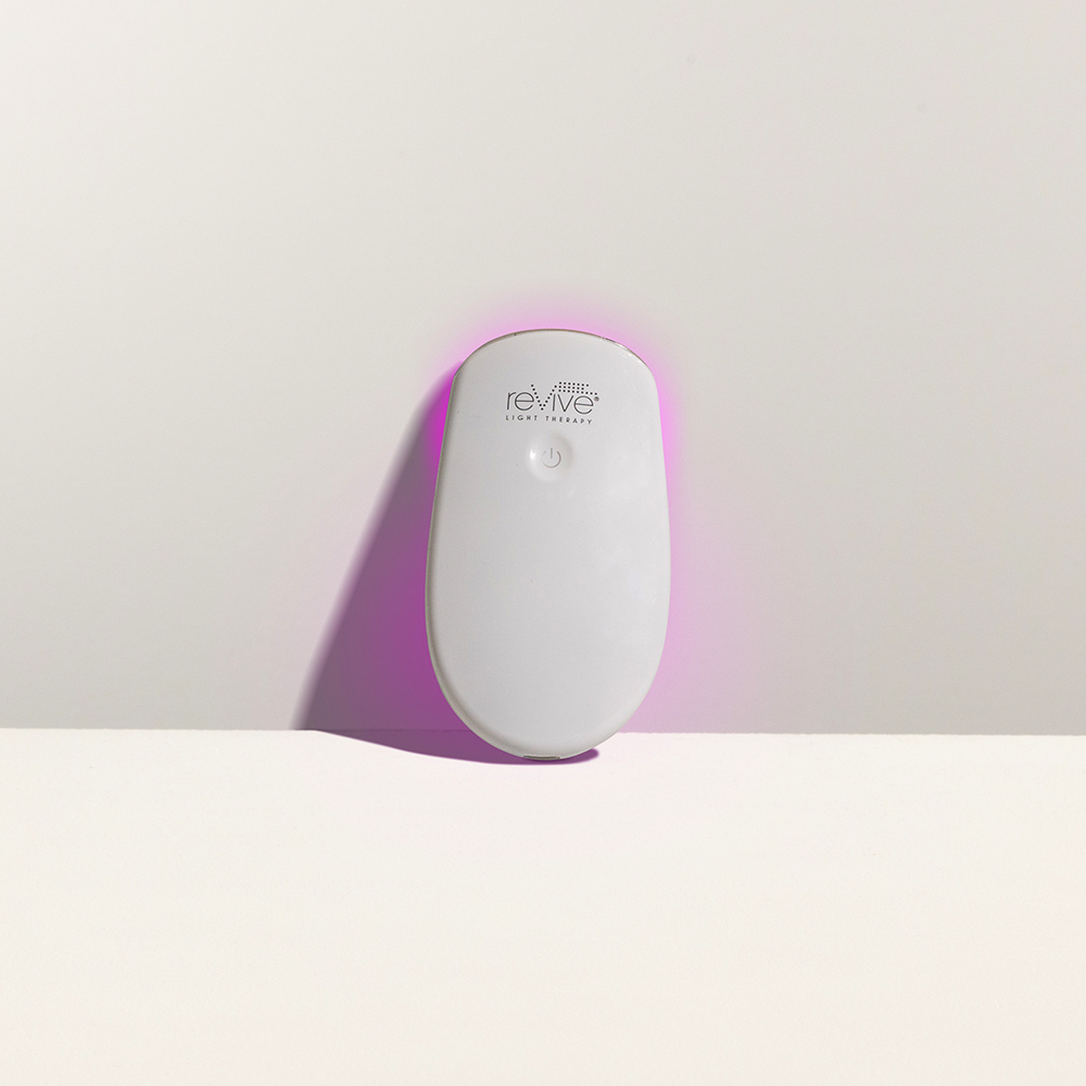 Lux Collection Essentials with LED lights on leans against a white background; the logo and power button faces the viewer while the purple light glows around the product