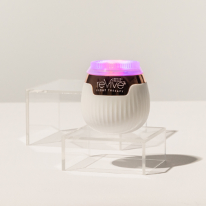 Lux Collection Sonique Mini sonique cleanser is sitting atop clear acrylic blocks with LED lights on.