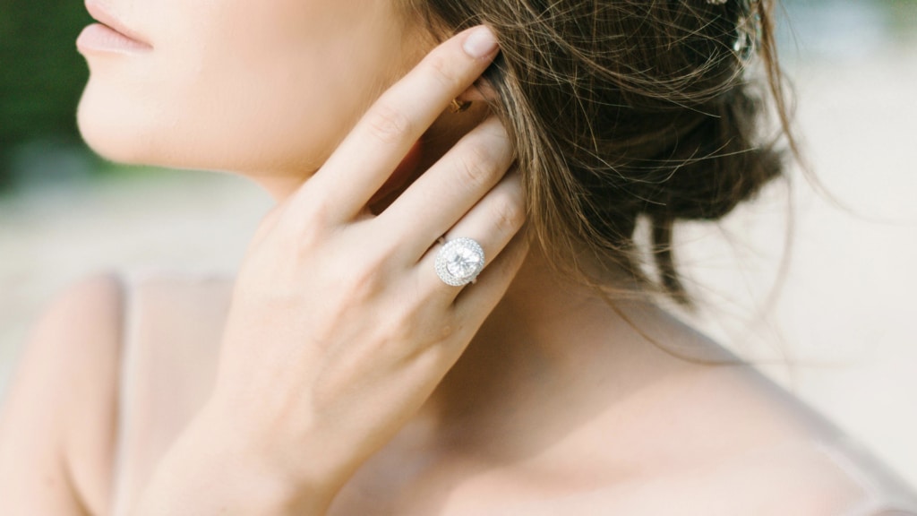 close up image of woman with engagement ring touching her hair