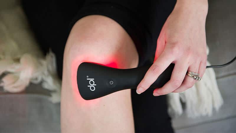 woman using red light therapy to relieve knee pain