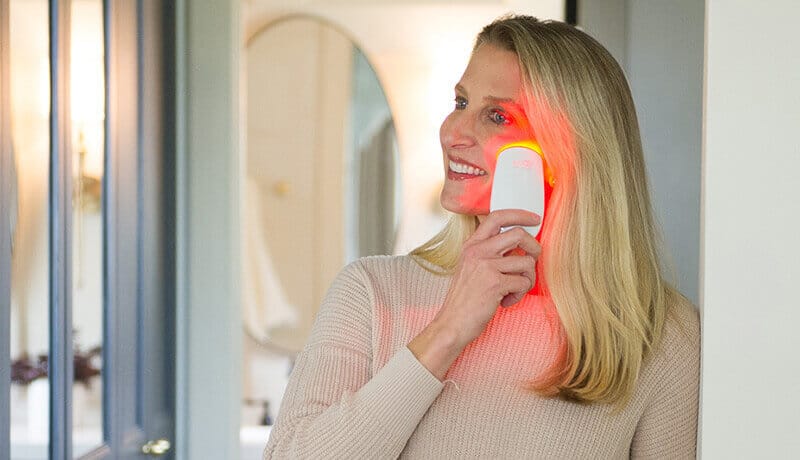 woman using red light therapy to treat crow's feet